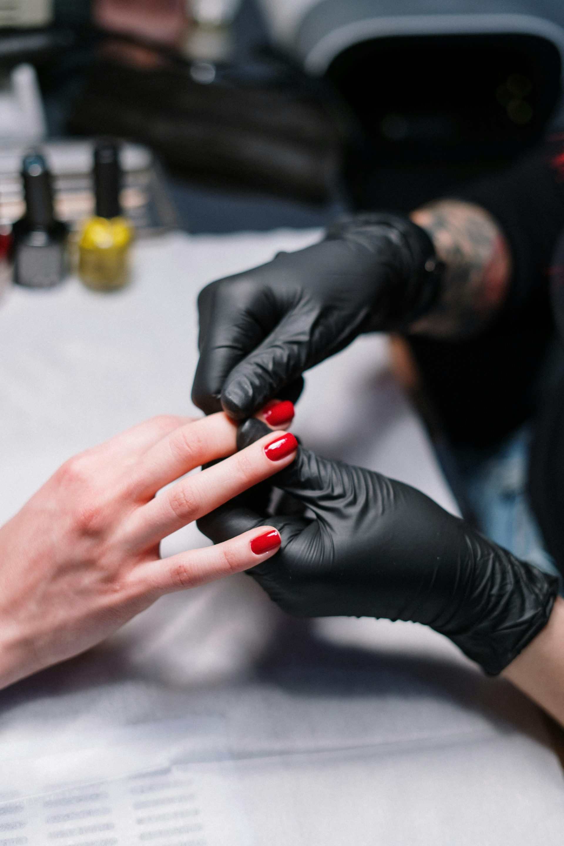 Especialista en manicura revisando uñas rojas de clienta
